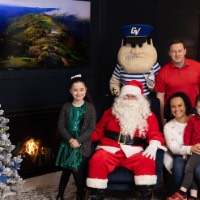 Little boy sitting on mom's lap with sister next to Santa and dad behind chair